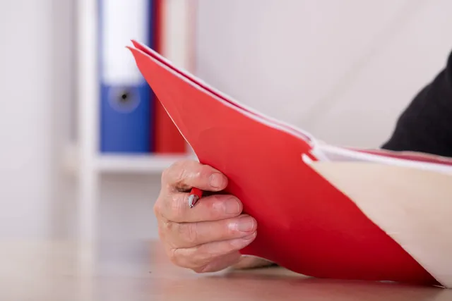 A person holding onto some red paper