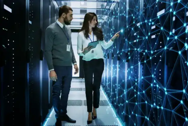 A man and woman are looking at the wall of data.
